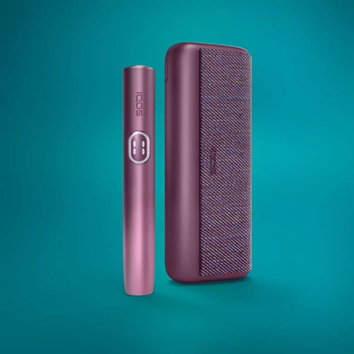 The image shows two IQOS devices in Garnet Red color. One device is standing upright, and the other is lying horizontally, both against a teal background.