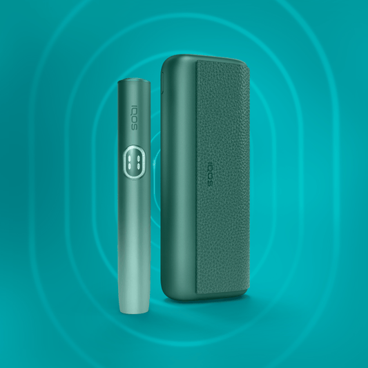 Aspen Green IQOS ILUMA i PRIME vaping device and its pod, displayed against a blue background with circular patterns.