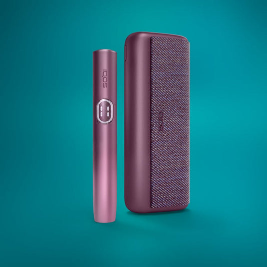 The image shows two IQOS devices in Garnet Red color. One device is standing upright, and the other is lying horizontally, both against a teal background.
