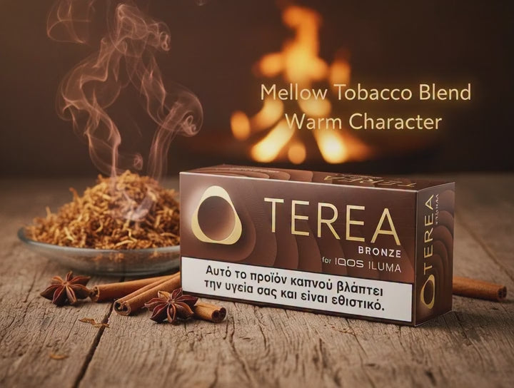 A box of Terea Bronze mellow tobacco blend for 100S Ilima, styled on a rustic wooden table with cinnamon sticks, star anise, and a bowl of loose tobacco with rising steam. The background features a warm, blurred fire, and text overlays read 'Mellow Tobacco Blend Warm Character'.