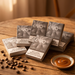 Five packs of EVO Eliffe disposable cigarettes arranged on a wooden table with scattered coffee beans and a small dish of caramel sauce. The packs are gray with white branding and health warning text.